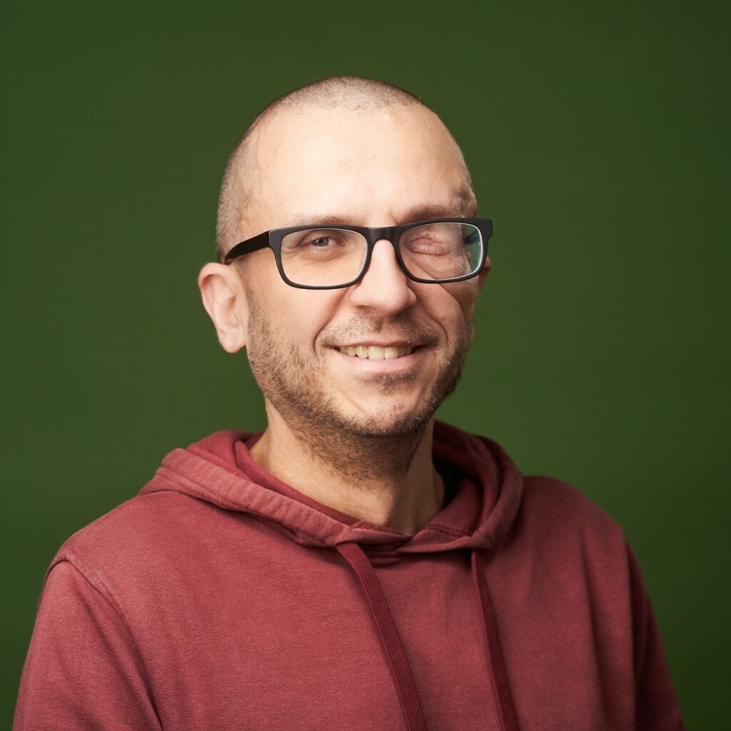 Foto von WordPress Experte Johannes Mairhofer mit rotem Hoodie vor grüner Wand
